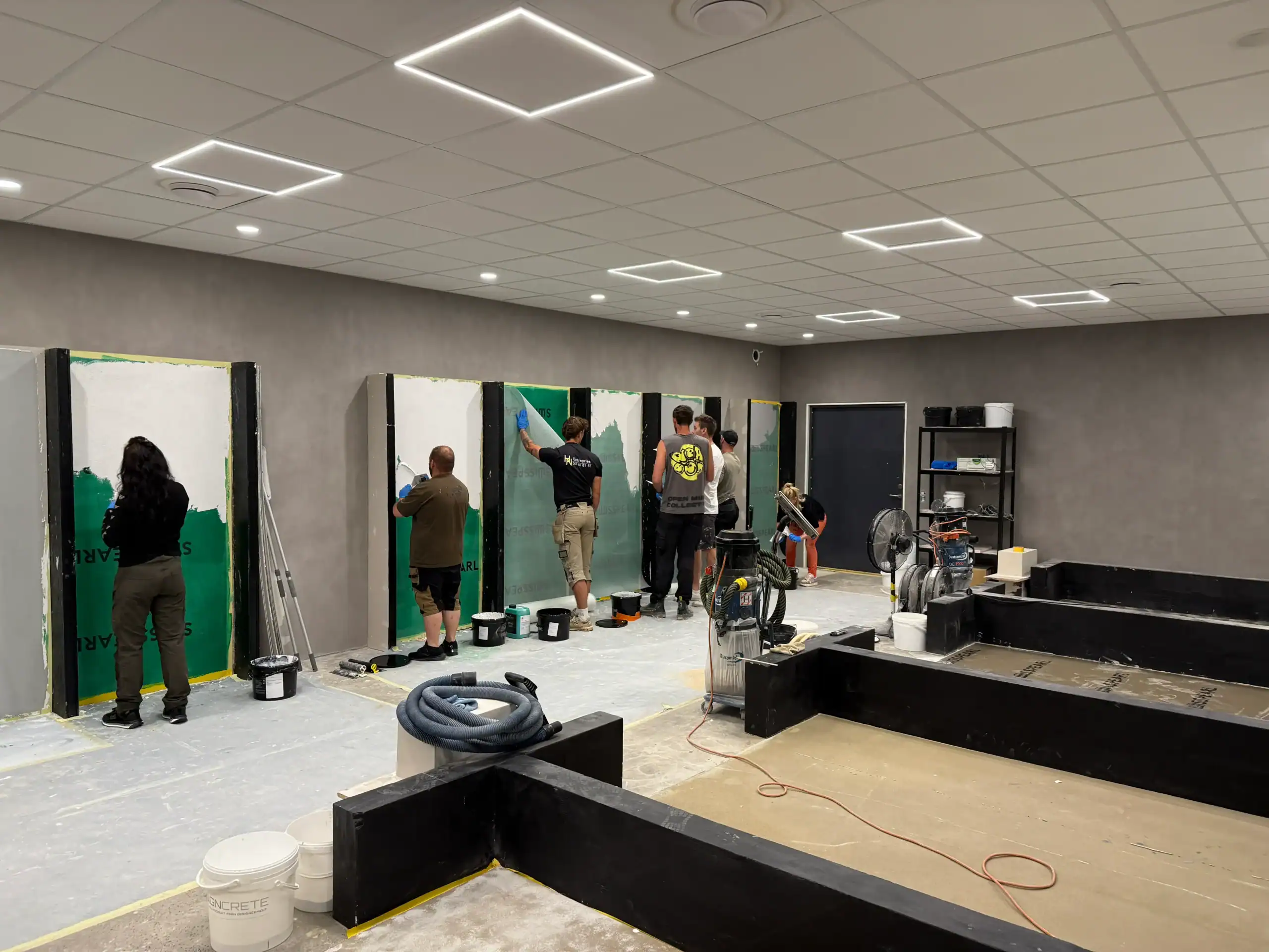 Kursdeltagare som applicerar microcement på väggar under microcement kurs